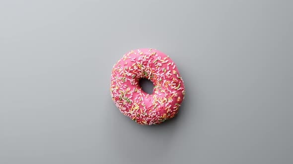 Fresh Tasty Sweet Delicious Doughnut Covered By Pink Icing Chocolate Rotating Isolated on Gray