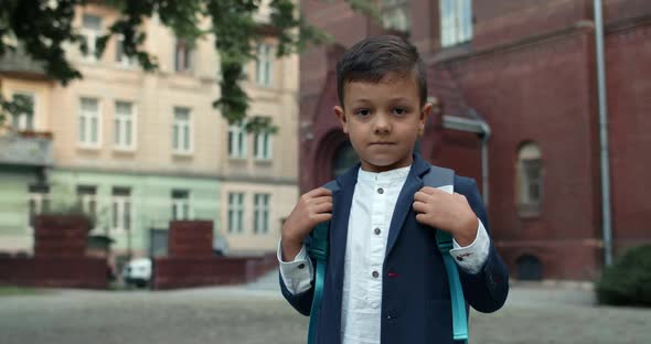 Portrait of Little Kid with Backpack Looking To Camera. Close Up View of Child Boy in Uniform Posing