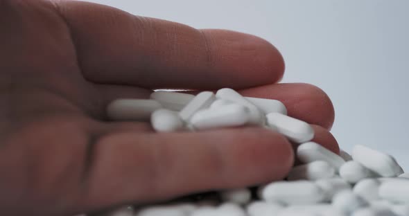 Palm Hand Full of White Scattering Pills. Capsules with Medicines on Light Background.