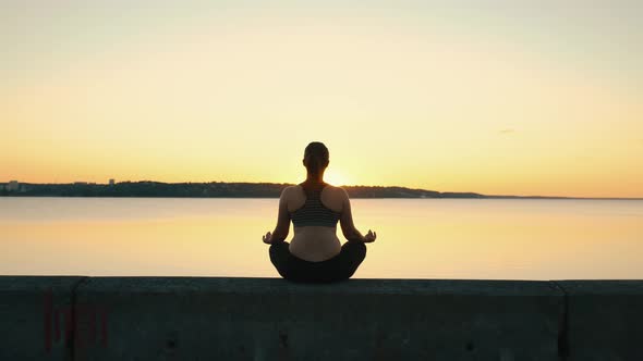 Silhouette of Young Woman Practicing Yoga on the Nature at Sunset