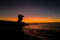 Silhouette of a Man wearing a cap standing on the coast overlooking sunrise in the ocean in Sydney - PhotoDune Item for Sale