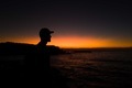 Silhouette of a Man wearing a cap standing on the coast overlooking sunrise in the ocean in Sydney - PhotoDune Item for Sale