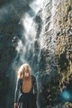 View from behind woman standing and looking at the waterfall in Hawaii - PhotoDune Item for Sale