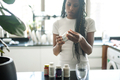 African American woman taking vitamins and supplements at home in her kitchen - PhotoDune Item for Sale