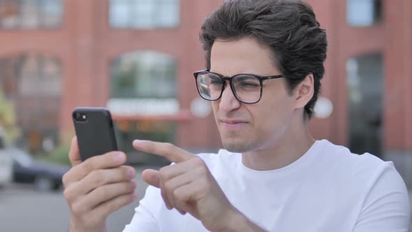 Outdoor Portrait of Young Man Upset By Loss on Smartphone