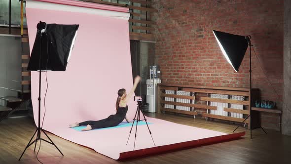 girl fitness blogger shows how to do exercises correctly on a pink background