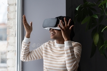 Virtual entertainment at home. Overjoyed african woman in vr headset playing interactive video game