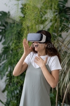 Virtual entertainment at home garden. Overjoyed woman in VR headset playing interactive video game