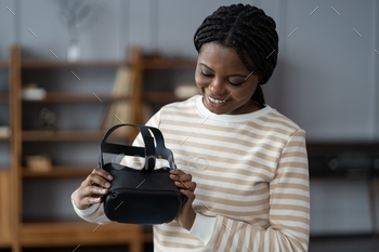 VR glasses in hands at home. Young african american lady testing modern virtual reality headset for video games. Future technology, augmented reality, using technology concept.