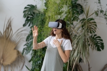 Virtual entertainment at home garden. Overjoyed woman in VR headset playing interactive video game