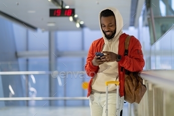 Smiling african american man traveler chatting in social media, waiting landing on board in airport