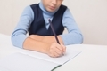 The schoolboy writes in a notebook, does his homework. Back to school concept. Close-up - PhotoDune Item for Sale