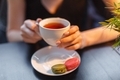 A young woman in a restaurant drinks tea with macaroons. Close-up dark photo. - PhotoDune Item for Sale