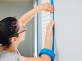 Young millennial woman at home taping white trim as preparation for painting the walls - PhotoDune Item for Sale