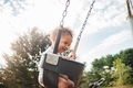 Mixed race baby boy at park enjoying being on the swing - PhotoDune Item for Sale