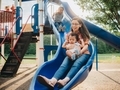 Young mother at the park having fun with her children on a blue slide  - PhotoDune Item for Sale