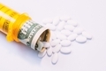 Pills coming out of a pill bottle with a twenty dollar bill inside, medical expense concept  - PhotoDune Item for Sale