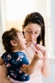 Young millennial mother at home in bathroom with diverse toddler girl brushing teeth together - PhotoDune Item for Sale