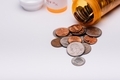 Cost of medication concept, coins coming out of pill bottle on white background  - PhotoDune Item for Sale