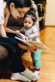 Parenthood, parenting, mother at home reading to her diverse toddler daughter, early education - PhotoDune Item for Sale