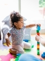 Diverse toddler girl at one happily playing with mega building blocks  - PhotoDune Item for Sale