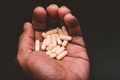 African American man holding a bunch of pills in hand against black background  - PhotoDune Item for Sale