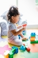 Diverse toddler girl at one happily playing with mega building blocks  - PhotoDune Item for Sale