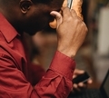 African American man in maroon shirt with credit card in hand and smartphone online shopping - PhotoDune Item for Sale