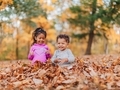 Mixed race siblings at the park playing in beautiful fall leaves, both having fun - PhotoDune Item for Sale