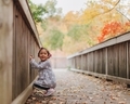 Little diverse girl on wooden bridge on a colorful fall day looking off camera at mother  - PhotoDune Item for Sale