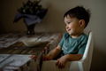 The baby eats semolina porridge at home in the kitchen - PhotoDune Item for Sale