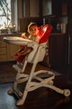 The baby sits in a highchair and eats orange - PhotoDune Item for Sale