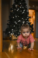 The baby is crawling at home against the background of a Christmas tree with garlands - PhotoDune Item for Sale