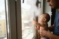 Baby and dad are looking out the window. Dad is holding a baby - PhotoDune Item for Sale