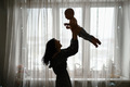 Silhouette of a mother with a baby in her arms in an apartment against the background of a window - PhotoDune Item for Sale