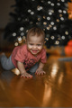 The baby is crawling at home against the background of a Christmas tree with garlands - PhotoDune Item for Sale