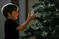 The boy decorates the Christmas tree for the New Year - PhotoDune Item for Sale