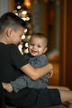 Happy children are sitting on a chair against the background of a Christmas tree. - PhotoDune Item for Sale