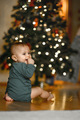 A one-year-old baby crawls at home against the background of a Christmas tree - PhotoDune Item for Sale