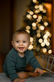 Portrait of a baby against the background of a Christmas tree. The child is crawling at home - PhotoDune Item for Sale
