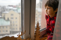 A five-year-old boy sits at home on the windowsill and looks out the window - PhotoDune Item for Sale