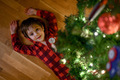 A five-year-old boy in red pajamas at home lies under the Christmas tree - PhotoDune Item for Sale