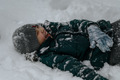 A teenager lies in the snow in winter. Children have fun and play with snow - PhotoDune Item for Sale