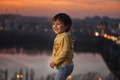 child at sunset on the river against the background of the city - PhotoDune Item for Sale