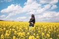 Portrait of young woman enjoying spring in a mustard field on sunny day - PhotoDune Item for Sale
