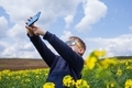 The boy takes pictures of the canola summer landscape on a smartphone. Children using technology - PhotoDune Item for Sale