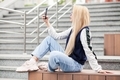 Young blond woman in casual clothes using social media on mobile phone  - PhotoDune Item for Sale