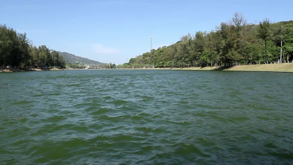 locked low angle shot of panoramic view of Nai Harn Lake on a breezy blue sky summer day, no people,