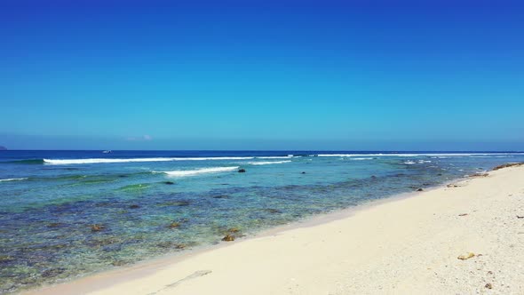 Tropical birds eye copy space shot of a sandy white paradise beach and aqua blue ocean background in