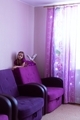 The girl is lying on the back of a purple armchair in a room with purple curtains and playing on the - PhotoDune Item for Sale